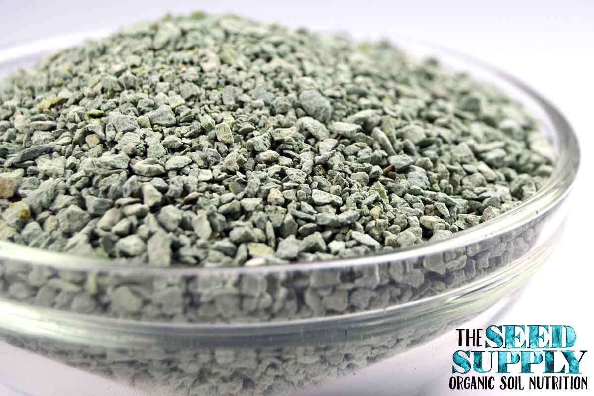 Close-up of pale green granular zeolite for improving soil structure and nutrient absorption.